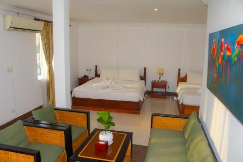 a bedroom with a bed and a couch and a table at The Blanc Residence in Siem Reap