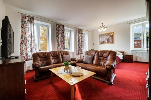 a living room with brown leather couches and a table at Wellness Penzion Zora Family in Tatranská Lomnica