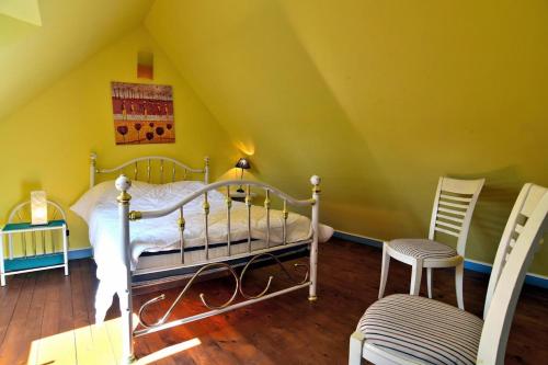 een slaapkamer met een bed en 2 stoelen op een zolder bij Maison de 2 chambres a Pluduno in Pluduno