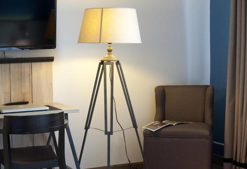 a floor lamp next to a chair and a desk at Dock1 in Regensburg