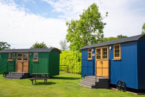 a group of three tiny houses in a field at Glamping at South Lytchett Manor in Poole
