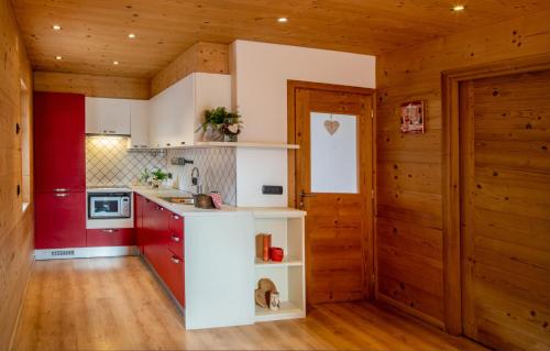 una cucina con armadi rossi e bianchi e pareti in legno di Appartamento Abete a Livigno