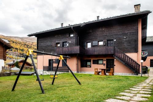 a house with a playground in front of it at Appartamento Abete in Livigno
