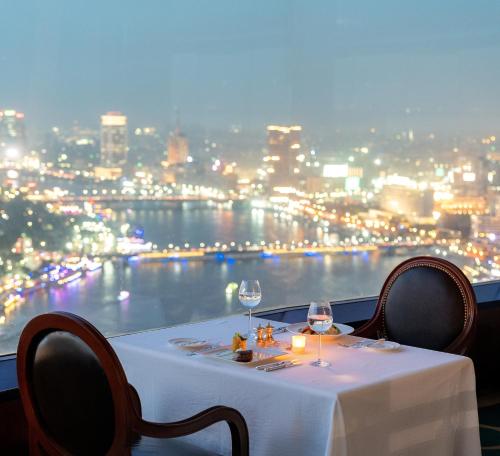 a table with two wine glasses and a view of the city at Hilton Cairo Grand Nile in Cairo