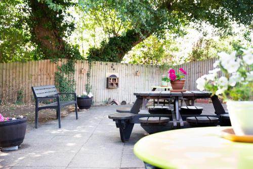 patio ze stołem, ławkami i ogrodzeniem w obiekcie Campanile Milton Keynes - Fenny Stratford w mieście Milton Keynes