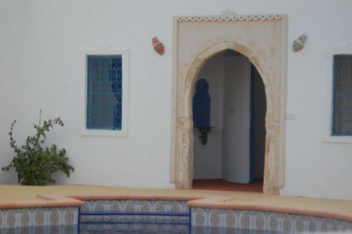 een ingang naar een wit gebouw met een blauwe deur bij Dar Aladin in Arkou