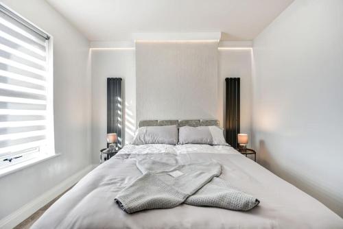 a white bedroom with a large bed with two lamps at Beauty Close to Coast, Stunning interior, By Air Premier in Newhaven