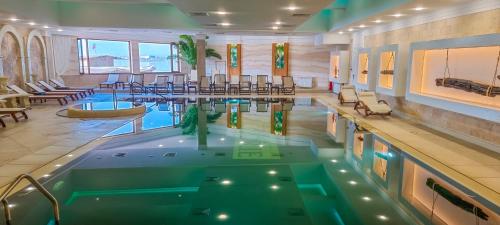 a pool in a hotel lobby with chairs and a swimming pool at Grand Hotel Pomorie - Medical spa in Pomorie