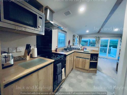 a kitchen with a stove and a microwave at 3-Bedroom Holiday Home with Valley Views in Newquay