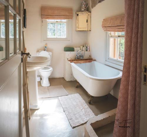 a bathroom with a tub and a sink and a toilet at The French Cottage in Clarens