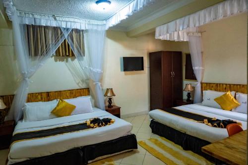Habitación de hotel con 2 camas con almohadas amarillas en Acacia Hotel Mbarara, en Mbarara