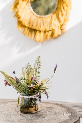 a vase with flowers on a table with a mirror at Can Vistabella Boutique Resort in San Antonio