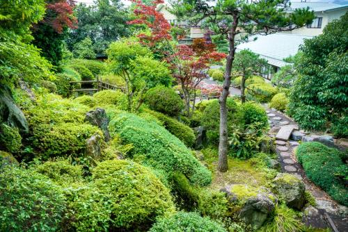 a garden with rocks and trees and bushes at Kaneyamaen in Fujiyoshida