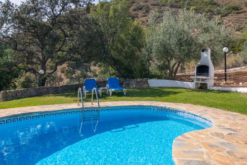 a swimming pool with two blue chairs in a yard at El Chorro Villas Casa Rosaleda in El Chorro