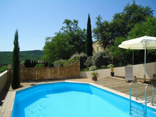 une piscine bleue avec un parasol et une maison dans l'établissement STUDIO TERRASSE PISCINE UZES PONT DU GARD, à Pougnadoresse