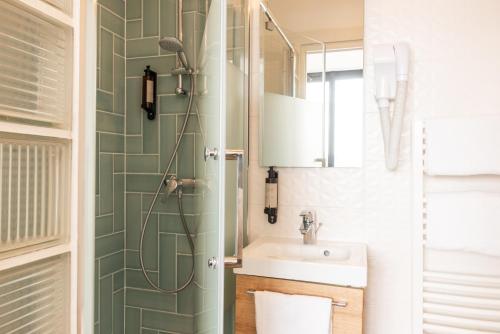 La salle de bains est pourvue d'un lavabo et d'une douche. dans l'établissement Hotel Terre Neuve, à Paris
