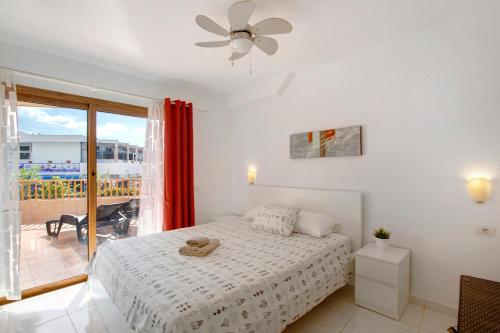 Habitación blanca con cama y balcón. en Los Geranios 304 en Adeje