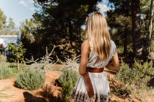 Eine Frau in einem weißen Kleid, die durch einen Garten geht. in der Unterkunft Can Vistabella Boutique Resort in Sant Antoni de Portmany