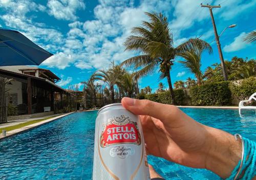 a person holding a soda can in front of a pool at Reserva do Paiva suites in Cabo de Santo Agostinho