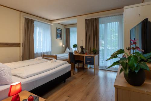 Cette chambre comprend un lit et un bureau. dans l'établissement Grischalodge das Hotel mit Bergblick seit 1929, à Parpan