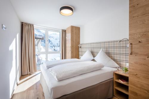 Schlafzimmer mit einem großen weißen Bett und einem Fenster in der Unterkunft All-Suite Resort Kühtai in Kühtai