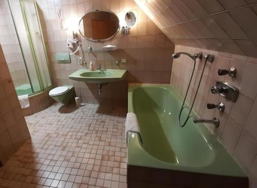 baño con bañera verde y lavamanos en Jasmin Privatzimmer, en Murau