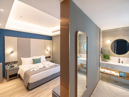 a bedroom with a large bed and a mirror at LanOu Hotel Qingdao Huangdao District Xinjiekou in Huangdao