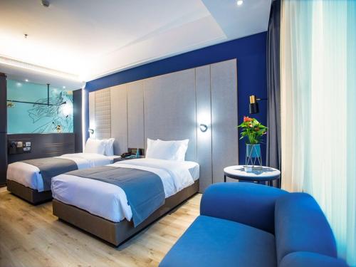 a hotel room with two beds and a couch at LanOu Hotel Jingzhou East Gate of Ancient City Wanda Plaza in Jingzhou