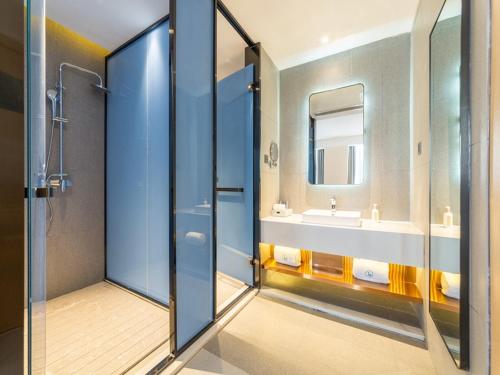 a bathroom with a shower and a sink and a mirror at LanOu Hotel Wanshan Tongren South Expressway Toll Station in Tongren