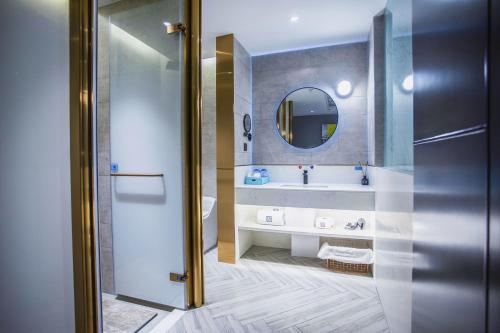W łazience znajduje się umywalka i lustro. w obiekcie LanOu Hotel Jingzhou East Gate of Ancient City Wanda Plaza w mieście Jingzhou
