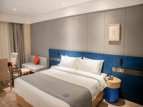 ein Hotelzimmer mit einem großen Bett und einem Stuhl in der Unterkunft LanOu Hotel Xiaonan District Wanda Plaza in Xiaogan