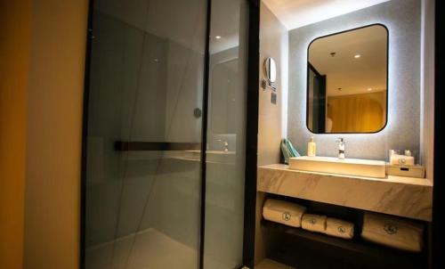 een badkamer met een douche, een wastafel en een spiegel bij LanOu Hotel Tianshui Bus Terminal Station in Tianshui