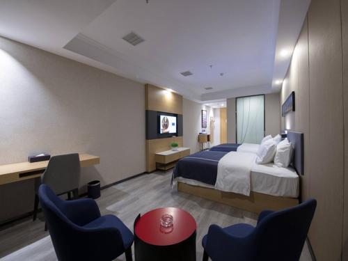 een hotelkamer met een groot bed en stoelen bij LanOu Hotel Yucheng Yingbin Avenue in Yuncheng