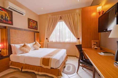 een slaapkamer met een bed en een bureau met een computer bij The Amariah Hotel & Apartments Mikocheni in Dar es Salaam