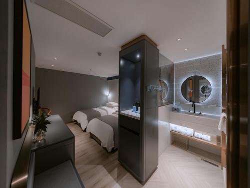 a hotel room with a bed and a mirror at LanOu Hotel Chaozhou Xiangqiao District Plaza in Chaozhou