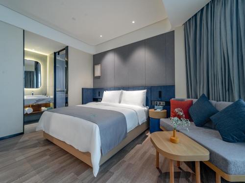 a bedroom with a large bed and a couch at LanOu Hotel Nanyang Wancheng Guangwu Emperor City in Nanyang