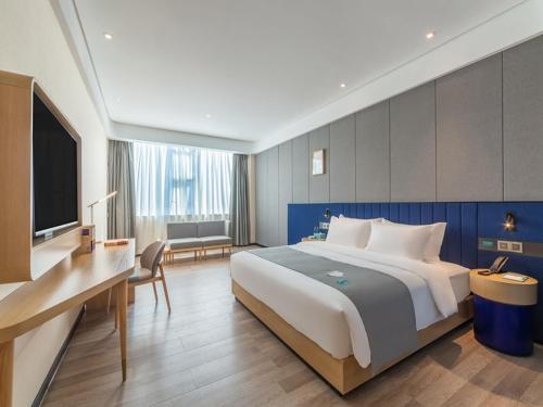 um quarto de hotel com uma cama grande e uma televisão em LanOu Hotel Wanshan Tongren South Expressway Toll Station em Tongren