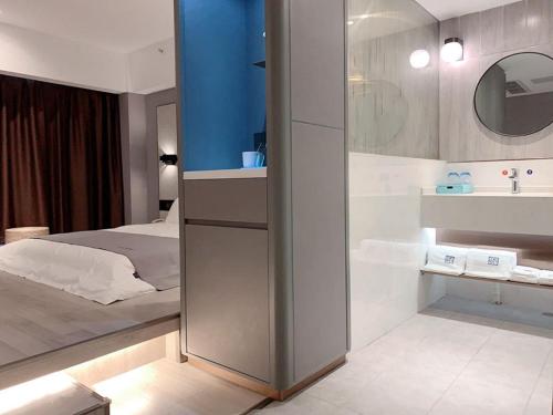 een slaapkamer met een bed en een badkamer met een wastafel bij LanOu Hotel Yancheng Dafeng Yongtai Plaza in Dafeng