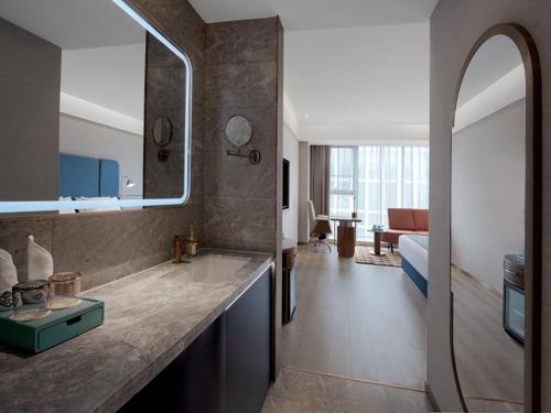 a bathroom with a sink and a living room at LanOu International Hotel Rizhao University Town in Rizhao