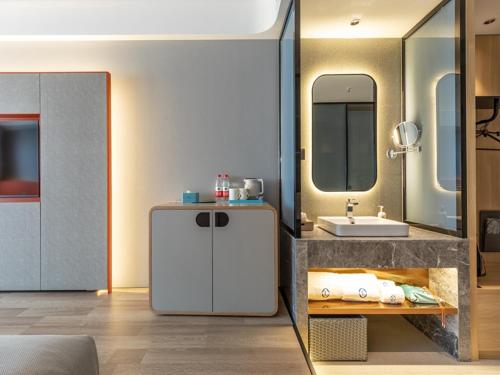 a bathroom with a sink and a mirror at LanOu Hotel Shanghai Sheshan National Forest Park Happy Valley in Songjiang