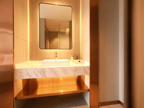 a bathroom with a sink and a mirror at LanOu Hotel Zhongning Weimin City Plaza in Jiangoushan