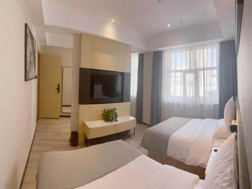 GolmudにあるLanOu Hotel Golmud Middle Bayi Roadのベッド2台、薄型テレビが備わるホテルルームです。