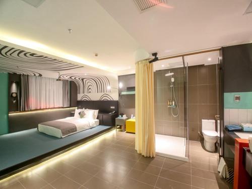a bedroom with a bed and a bathroom with a shower at LanOu Hotel Zhangye Hexi College Ganquan Park in Zhangye