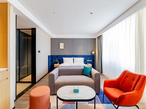 呼和浩特的住宿－呼和浩特新城区摩尔城兰欧尚品酒店，酒店客房配有一张床、一张沙发和椅子。
