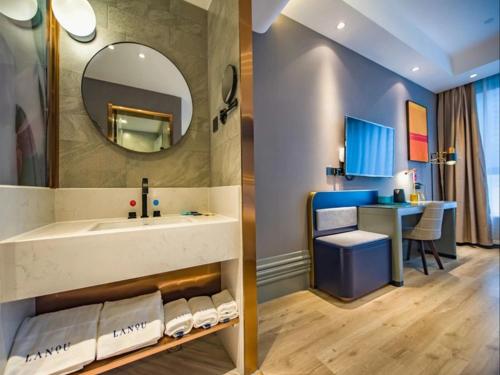 ein Bad mit einem Waschbecken, einem Spiegel und einem Schreibtisch in der Unterkunft LanOu Hotel Heze Mudan District University Town in Heze