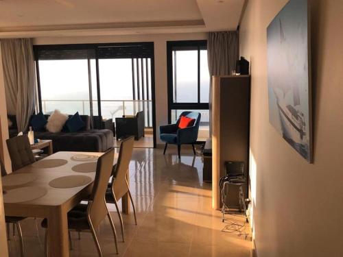 a living room with a table and chairs and a living room at Superbe appartement vue sur mer in Sale