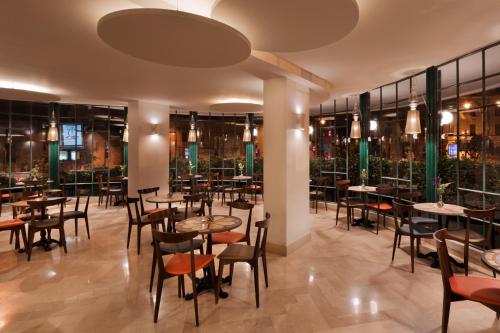 un restaurante con mesas, sillas y ventanas en Prima Kings Hotel, en Jerusalén