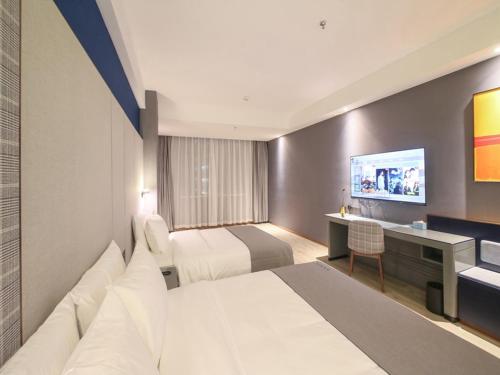 a hotel room with two beds and a desk at LanOu Hotel Zhangye Hexi College Ganquan Park in Zhangye