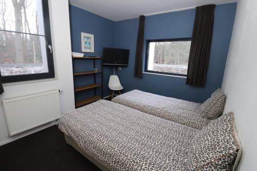 a blue bedroom with two beds and a window at Avellano in Helmond