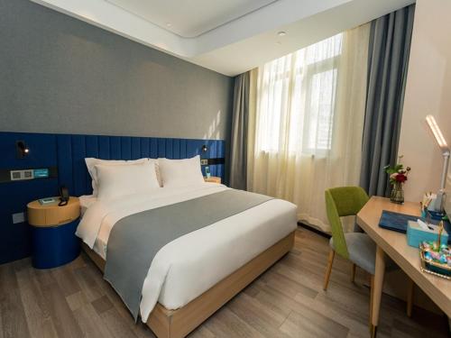 um quarto de hotel com uma cama grande e uma secretária em LanOu Hotel Huai'an Jinhu Suning Plaza West Health Road em Jinhu